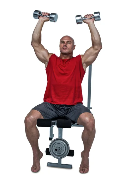 Muscular man exercising while sitting on bench press — Stock Photo, Image