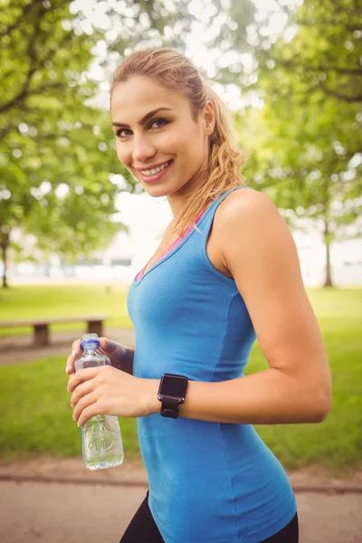 Jogging yapan kadın holding su şişesi gülümseyen portresi — Stok fotoğraf