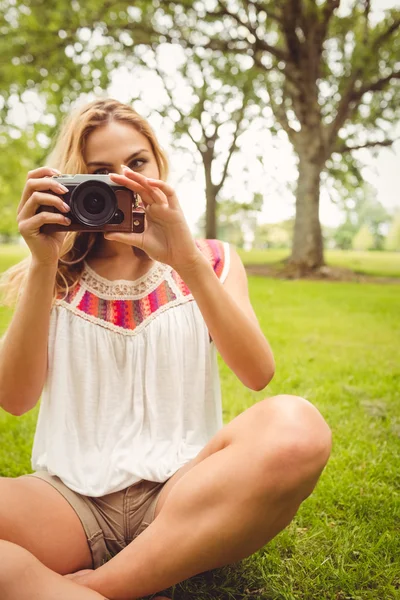 Femme tenant la caméra tout en étant assis sur l'herbe — Photo