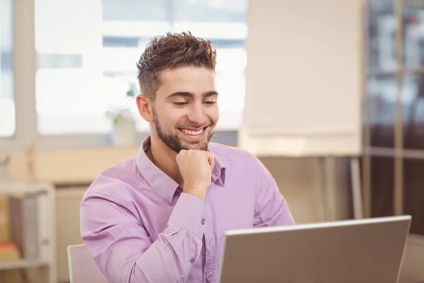 Biznesmen z ręki na brodę patrząc na laptopa — Zdjęcie stockowe