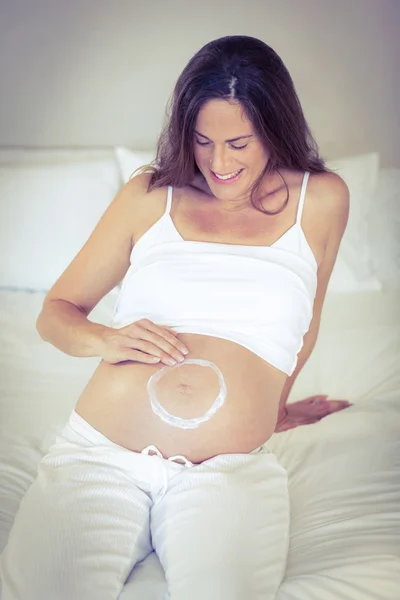 Happy woman making circle with lotion on belly — Stock Photo, Image