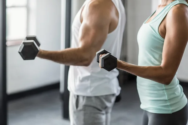 Mitten delen av paret tränar med hantlar i gym — Stockfoto