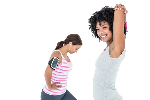 Woman stretching while female friend exercising — Stock Photo, Image