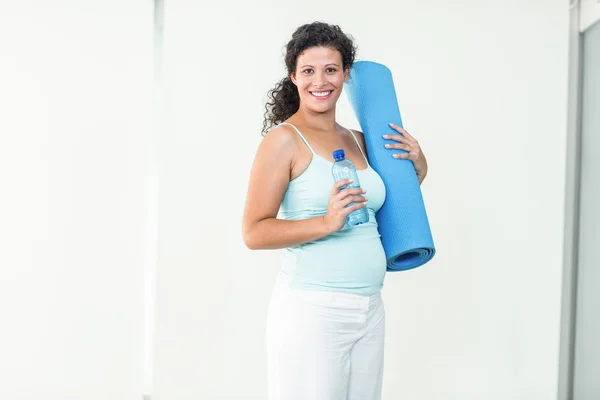 Улыбающаяся беременная женщина держит матрас — стоковое фото