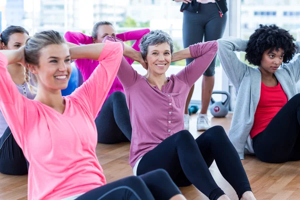 Mulheres felizes fazendo sit ups no chão de madeira — Fotografia de Stock