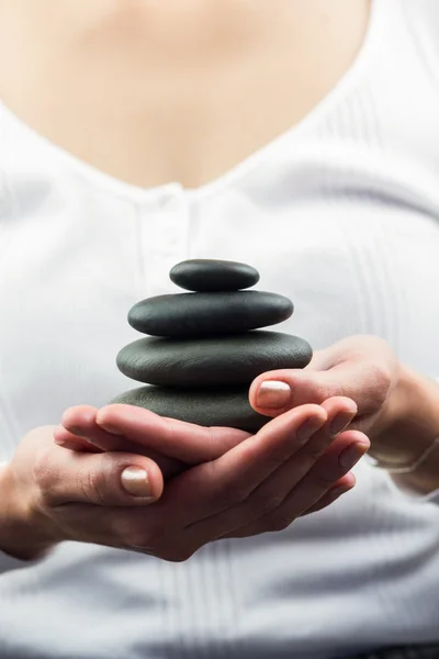 Mid section of woman holding black pebbles — Stock Photo, Image