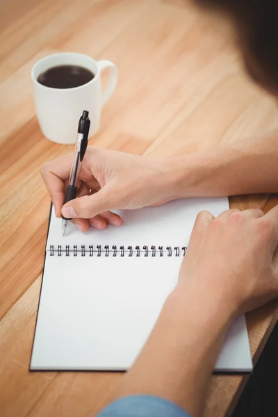 Hipster schrijven op spiraal notebook op balie in kantoor — Stockfoto