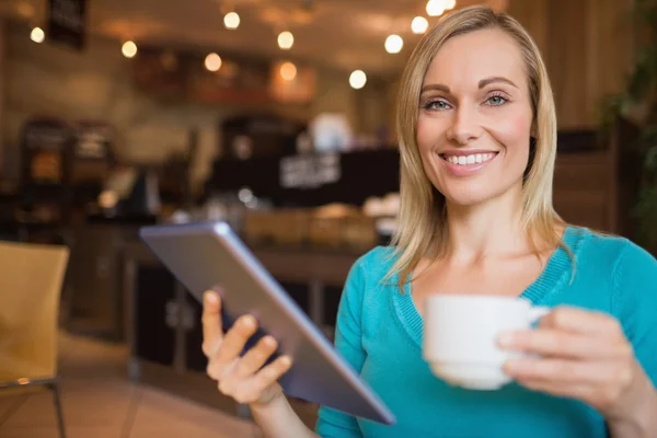 Mujer joven usando tableta digital mientras sostiene la taza — Foto de Stock