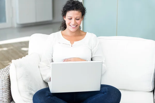 Szczęśliwa kobieta z laptopem na kanapie — Zdjęcie stockowe