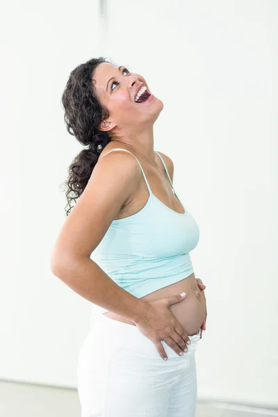 Pregnant woman looking up while touching her belly — Stock Photo, Image