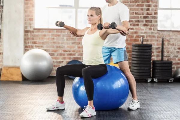 Male trainer helping young woman with the dumbbells — Stock Photo, Image