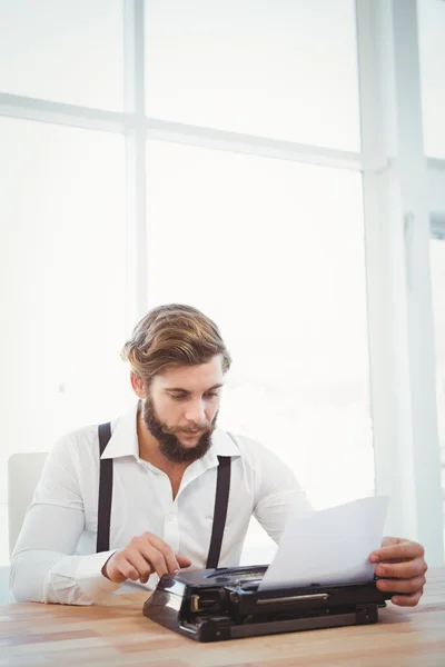 Hipster using typewriter at desk in office — Stock Photo, Image