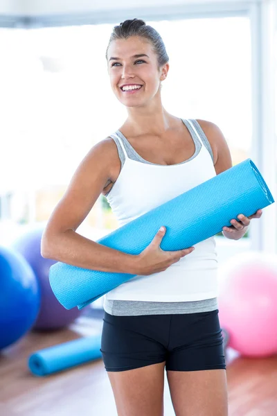 Bella donna sorridente mentre tiene in mano tappetino yoga — Foto Stock