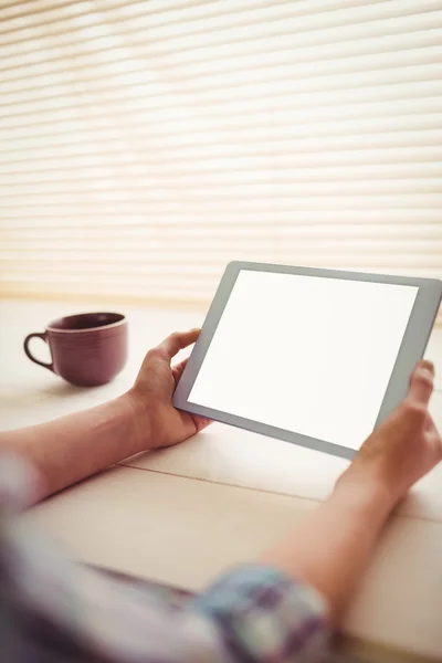 Hände halten digitales Tablet nach Kaffeetasse auf Tisch — Stockfoto