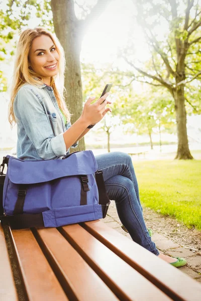 Портрет улыбающейся женщины, держащей смартфон в парке — стоковое фото