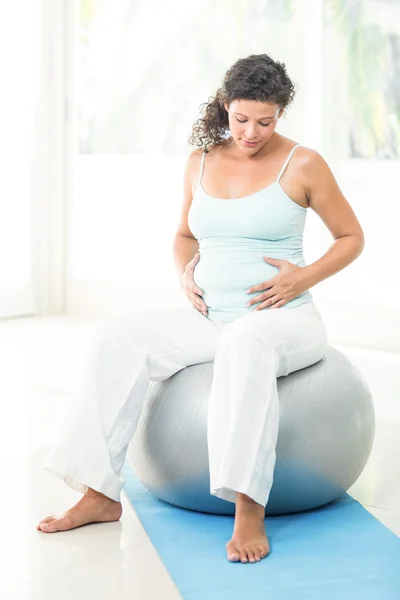 Gravid kvinna röra hennes mage medan du sitter på övning boll — Stockfoto