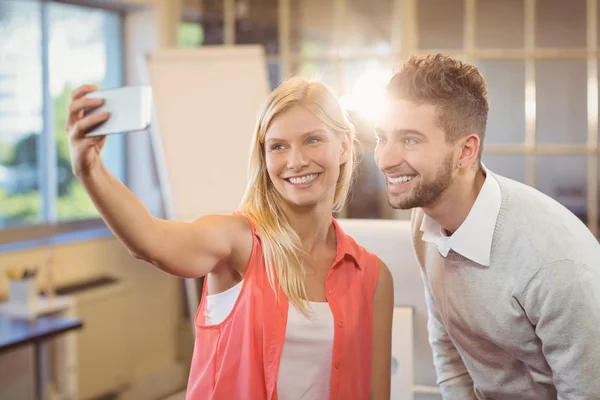 Empresária tomando selfie com colega do sexo masculino — Fotografia de Stock