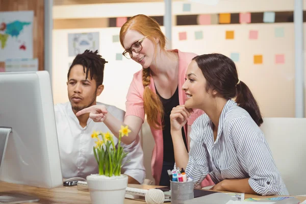 Businesswoman showing something to colleagues on computer — Stock Photo, Image