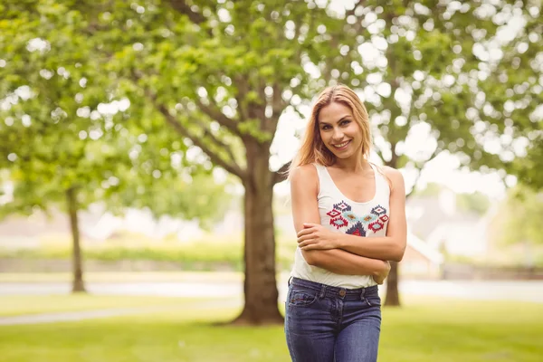 Porträtt av leende kvinna med armar korsade stående på gräs — Stockfoto