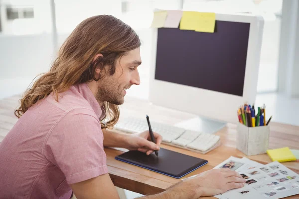 Hipster grafisch tablet gebruiken terwijl u werkt aan balie — Stockfoto