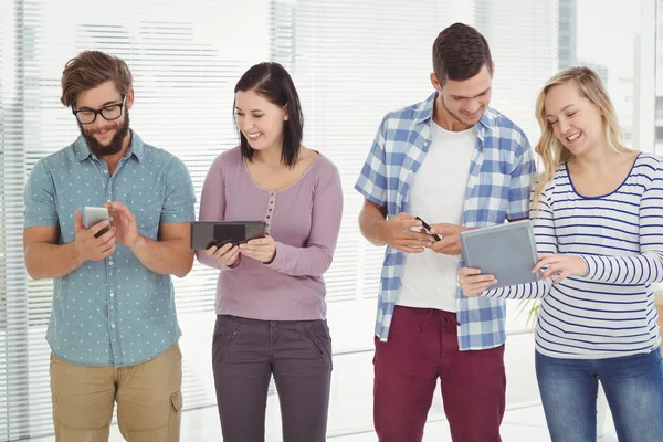 Smiling business people using electronic gadgets — Stock Photo, Image