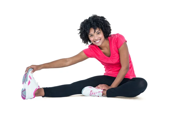 Portrait of young woman touching toes while exercising — Stock Photo, Image