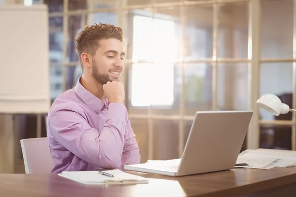 Affärsman med hand på hakan arbetar med laptop — Stockfoto