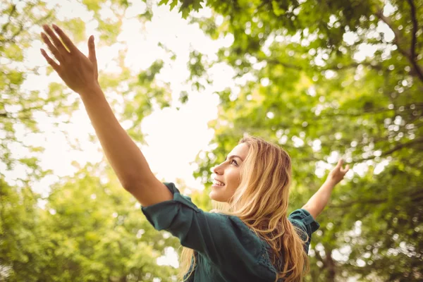 Schöne lächelnde Frau mit erhobenen Armen im Park — Stockfoto