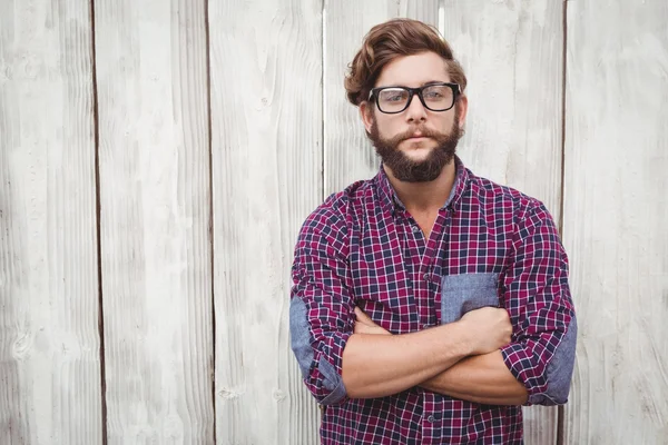 Säker hipster bär glasögon med armarna korsade — Stockfoto