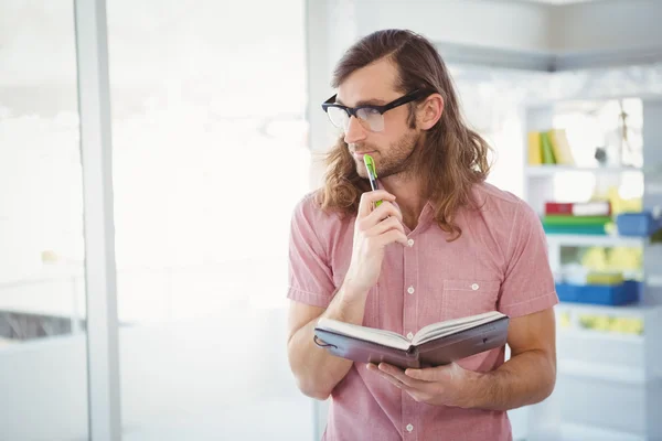 Pensativo hipster segurando caneta e livro — Fotografia de Stock