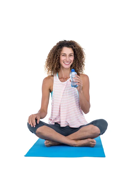 Mujer joven con botella de agua sentada en la esterilla de ejercicio —  Fotos de Stock
