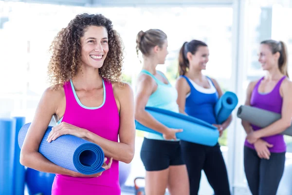 Mulher sorrindo enquanto segurando tapete de exercício — Fotografia de Stock