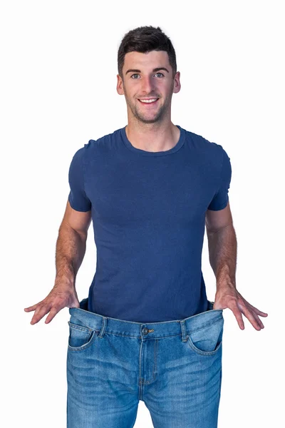 Bonito homem mostrando jeans jeans jeans soltos — Fotografia de Stock