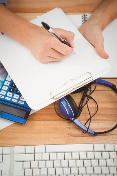 Empresario escribiendo en papel en portapapeles —  Fotos de Stock