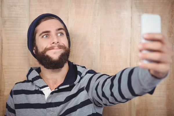 Хипстер делает лицо, делая селфи на мобильном телефоне — стоковое фото
