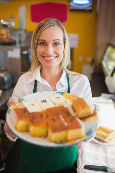 Boldog női munkavállaló, amely süteményeket, lemez — Stock Fotó
