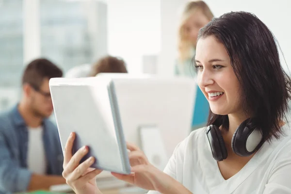 Femme souriante avec écouteurs utilisant une tablette numérique — Photo