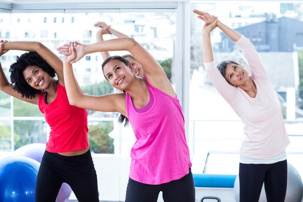 Mujeres sonrientes haciendo ejercicio con los brazos levantados — Foto de Stock