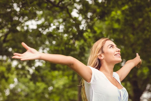 Donna sorridente con le braccia alzate nel parco — Foto Stock