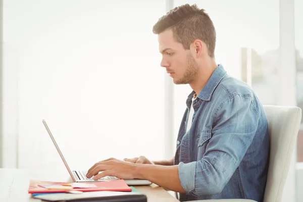 Vista lateral do jovem trabalhando no laptop — Fotografia de Stock