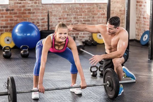 Woman lifting barbell with her trainer — Stock Photo, Image