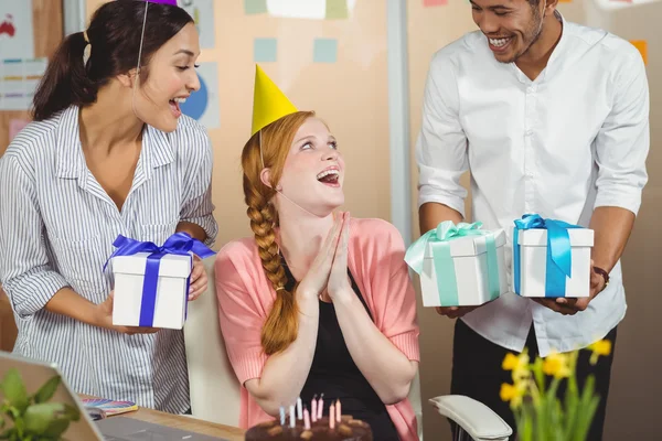 Colegas felizes com presentes olhando para mulher de negócios — Fotografia de Stock