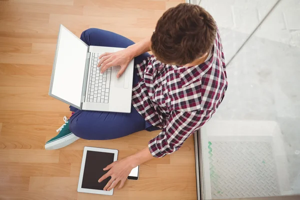 Hipster siedzi z laptopa na górze podczas używania cyfrowego tabletu — Zdjęcie stockowe