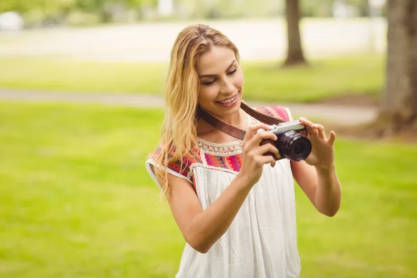 Femme souriante regardant appareil photo numérique tout en se tenant sur l'herbe — Photo