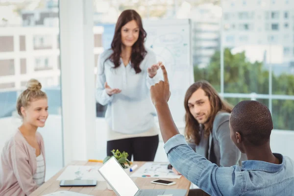 Mann mit erhobener Hand im Gespräch mit Mitarbeitern — Stockfoto