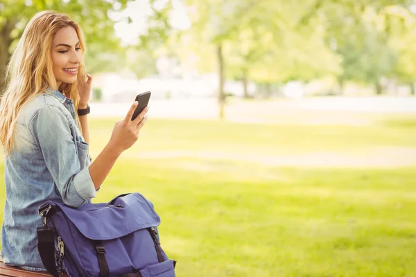 Lächelnde Frau benutzt Smartphone im Park — Stockfoto