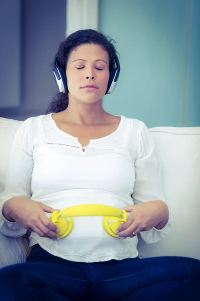 Kvinna sitter med ögonen stängda lyssnar musik — Stockfoto