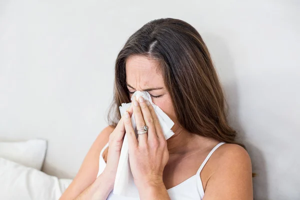 Woman sneezing with tissue on mouth — Stock Photo, Image