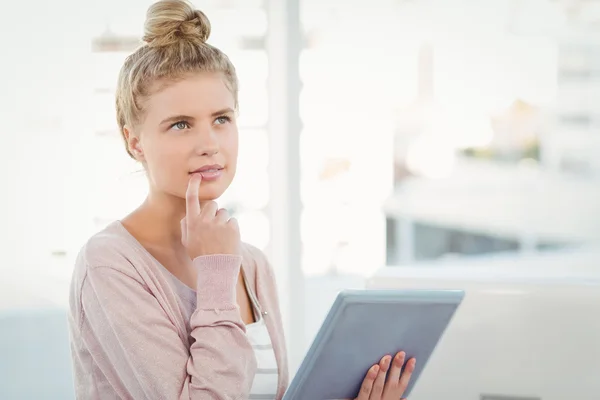 Mujer reflexiva sosteniendo tableta digital en la oficina —  Fotos de Stock