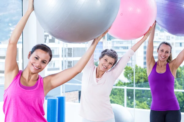 Mulheres segurando bolas de exercício com os braços levantados — Fotografia de Stock